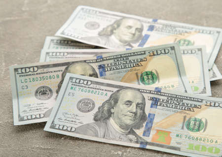 A pile of hundred dollar bills on gray. Top view