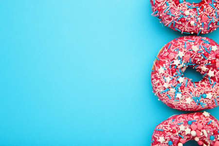 Donuts with icing on pastel blue background. Top view.の写真素材