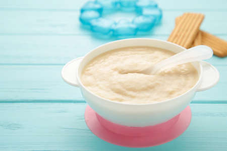 Bowl with baby food with toys on blue background. Top viewの写真素材