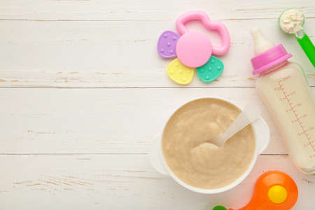 Bowl with baby food and milk with toys on white background. Top viewの写真素材