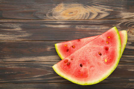 Fresh ripe striped sliced watermelon on brown wooden background.の写真素材