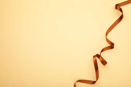 Brown ribbon on beige background with copy space. Top viewの写真素材