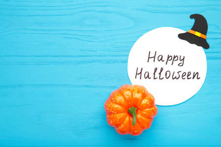 Happy Halloween inscription with pumpkin on blue background. Top view