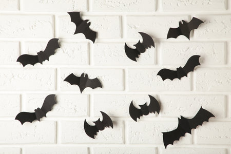 Halloween, decoration and scary concept - black paper bats flying over white background