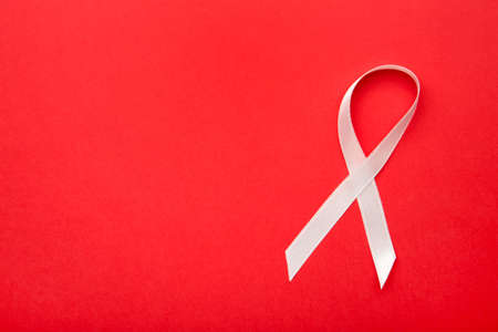 Pink satin breast cancer awareness ribbons on red background. Top view.