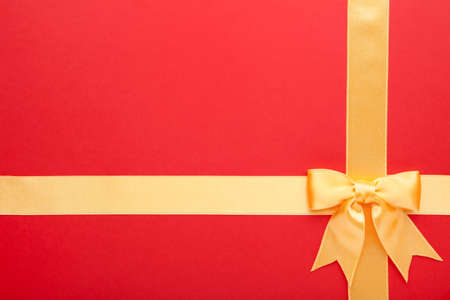 Beautiful gold ribbon and bow on red background. Top view.の写真素材