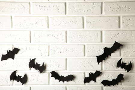 Halloween, decoration and scary concept - black paper bats flying over white background