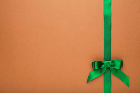 Green handmade ribbon with bow on brown background.の写真素材