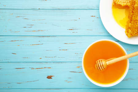 Bowl of honey with honeycomb on blue wooden table. Top viewの写真素材