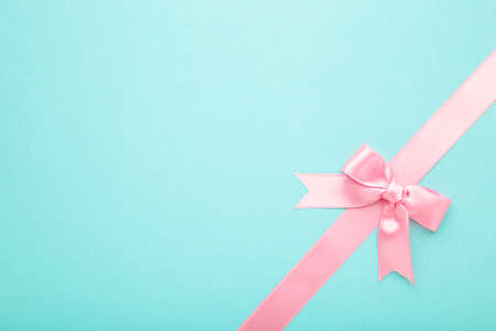 Pink pastel ribbon with bow isolated on a blue background. Top view.の写真素材
