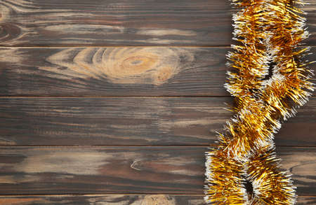 Christmas gold tinsel on brown wooden background. Top view.の写真素材