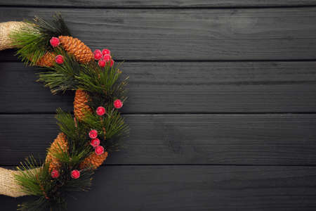 Green christmas wreath decorated with red viburnum on black wooden background. Thanksgiving Day.
