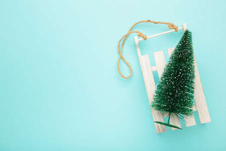 Christmas background with sleigh and fir-tree on blue wooden background. Top view.