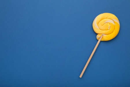 Yellow spiral lollipop on blue background. Top viewの写真素材