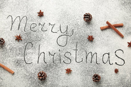 Merry Christmas text made with flour with decorations on a black stone cutting board. Top viewの写真素材