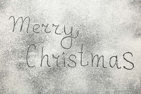 Christmas composition. Merry christmas text made with flour on black background, snow, december, top view, flat layの写真素材