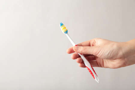 Toothbrush in woman's hand on gray background. Top viewの写真素材