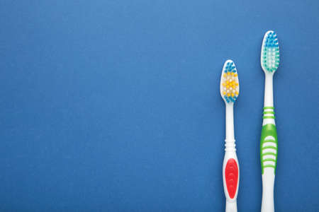 Two toothbrushes on blue background with copy space. Top view