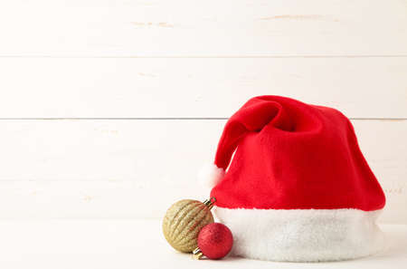 Santa Claus red hat and christmas toys on white wooden background. Top view.