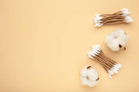Cotton ear sticks with flower on beige with copy space. Top viewの写真素材