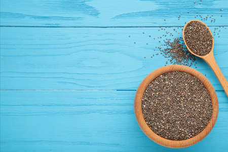 Healthy Chia seeds in a wooden spoon and bowl on blue. Top viewの写真素材