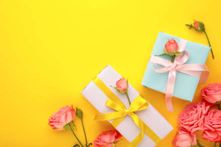 Valentines day background with pink roses and gift box on yellow background. Top view with copy...