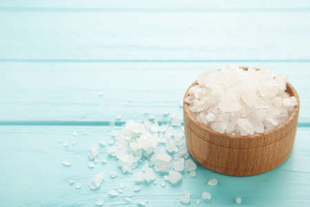 Sea salt in bowl on blue background. Top view