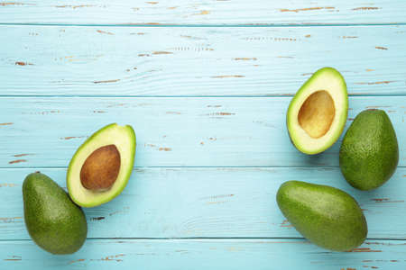 Fresh avocado and half of avocado on blue background. Top view