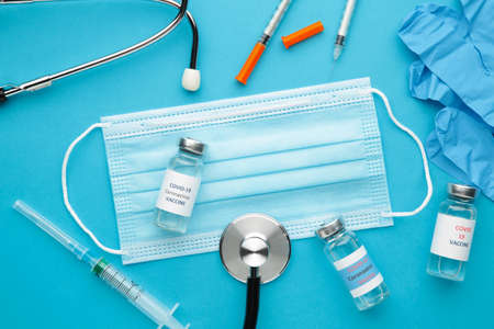 vaccine vials, syringe, medical gloves and stethoscope on blue background. Vaccination session and immunity improvement. Top viewの写真素材