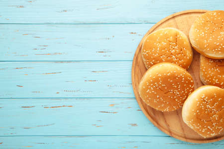 Burger buns on cutting board on a blue wooden background. Top view.