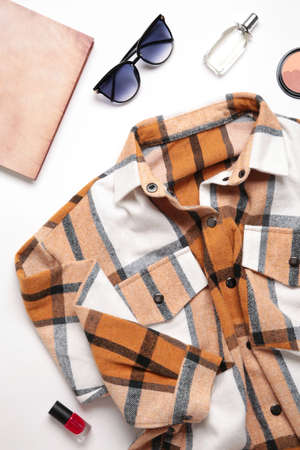Multi-colored checkered women's shirt with accessories on a light background. Top view
