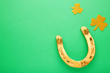 Green clovers and gold horseshoe on green background for St. Patrick's Day Holiday. Top view.の写真素材