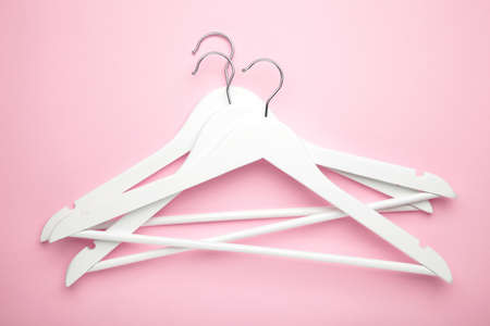 Many wooden white hangers on pink background. Store concept, empty hanger.