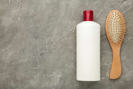 Hair styling concept with shampoo and combs on gray background. Flat lay, top view