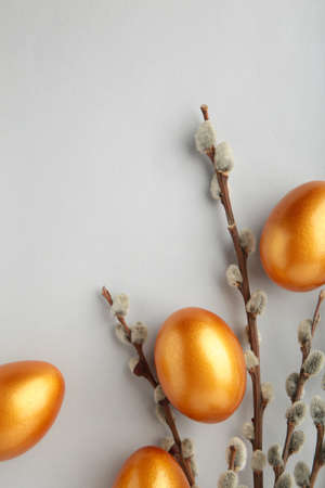 Gold Easter eggs and willow branches on gray background. Top view.の写真素材