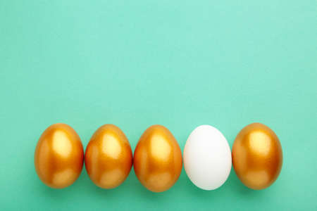Gold egg with white on mint background. Top viewの写真素材