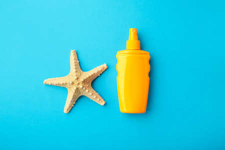 Sun protection bottle with starfish on blue background. Top view.の写真素材