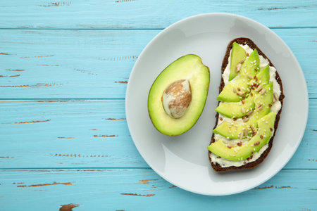 Avocado sandwich on dark rye bread made with half of avocado on blue background. Top view