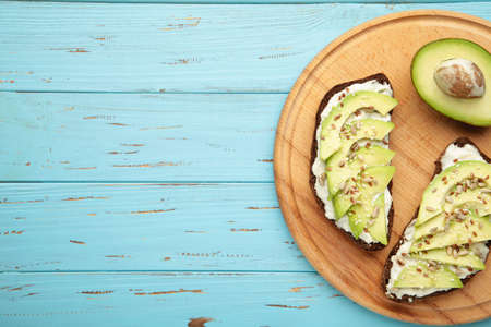 Avocado sandwich on dark rye bread made with fresh sliced avocados on blue wooden background. Top viewの写真素材