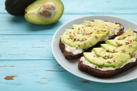 Avocado sandwich on dark rye bread made with fresh sliced avocados on blue background. Top view
