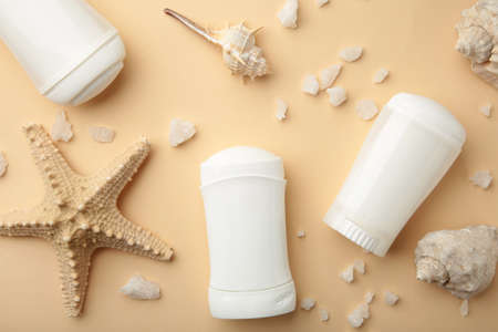 Deodorants for women and seashells on beige background. Top viewの写真素材