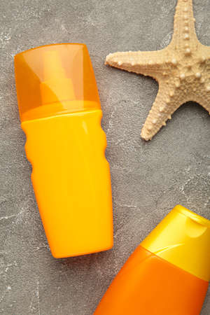 Sun protection bottles with starfish on gray background. Top view.