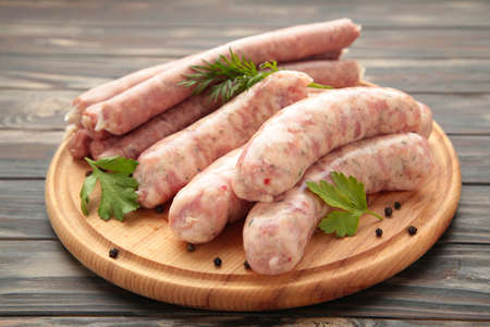 Raw sausage on cutting board on brown background.の写真素材