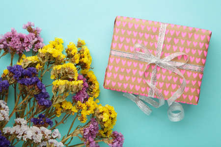 Gift or present box and flower on blue background. Pastel color. Greeting card with copy space. Top viewの写真素材