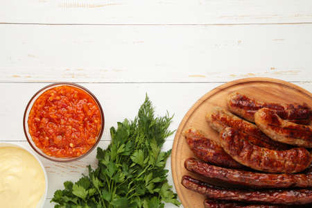 Grilled sausages on wooden board on white background. Top view