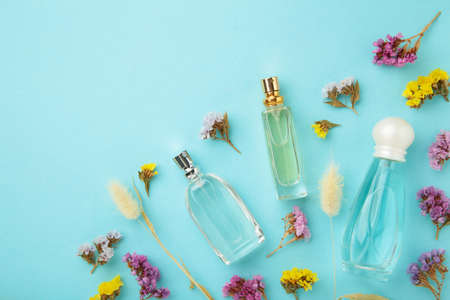 Bottle of perfume with flowers on blue background. Top viewの写真素材