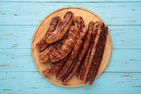 Grilled sausages on wooden board on blue background. Top viewの写真素材