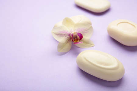 Different white soaps with flowers. A lot of solid soap for hygiene and cleanliness on purple background. Top view.の写真素材