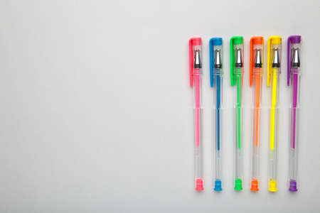 Different colors pens on gray backgroundwith copy space. Top view