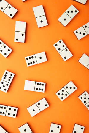 Playing dominoes on a orange table. Domino effect. Vertical photoの写真素材